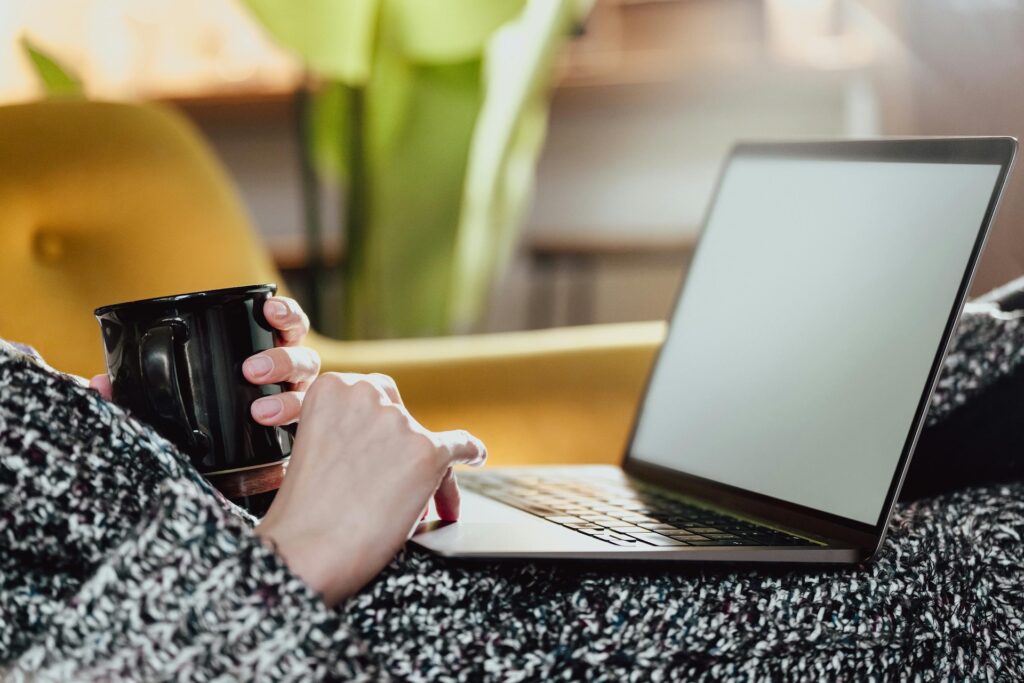 Hands of Woman Holding Cup and Laptop