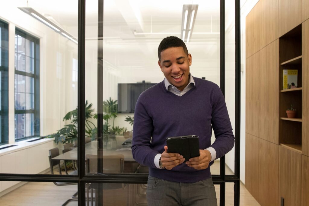 smiling man standing outside an office with a tablet