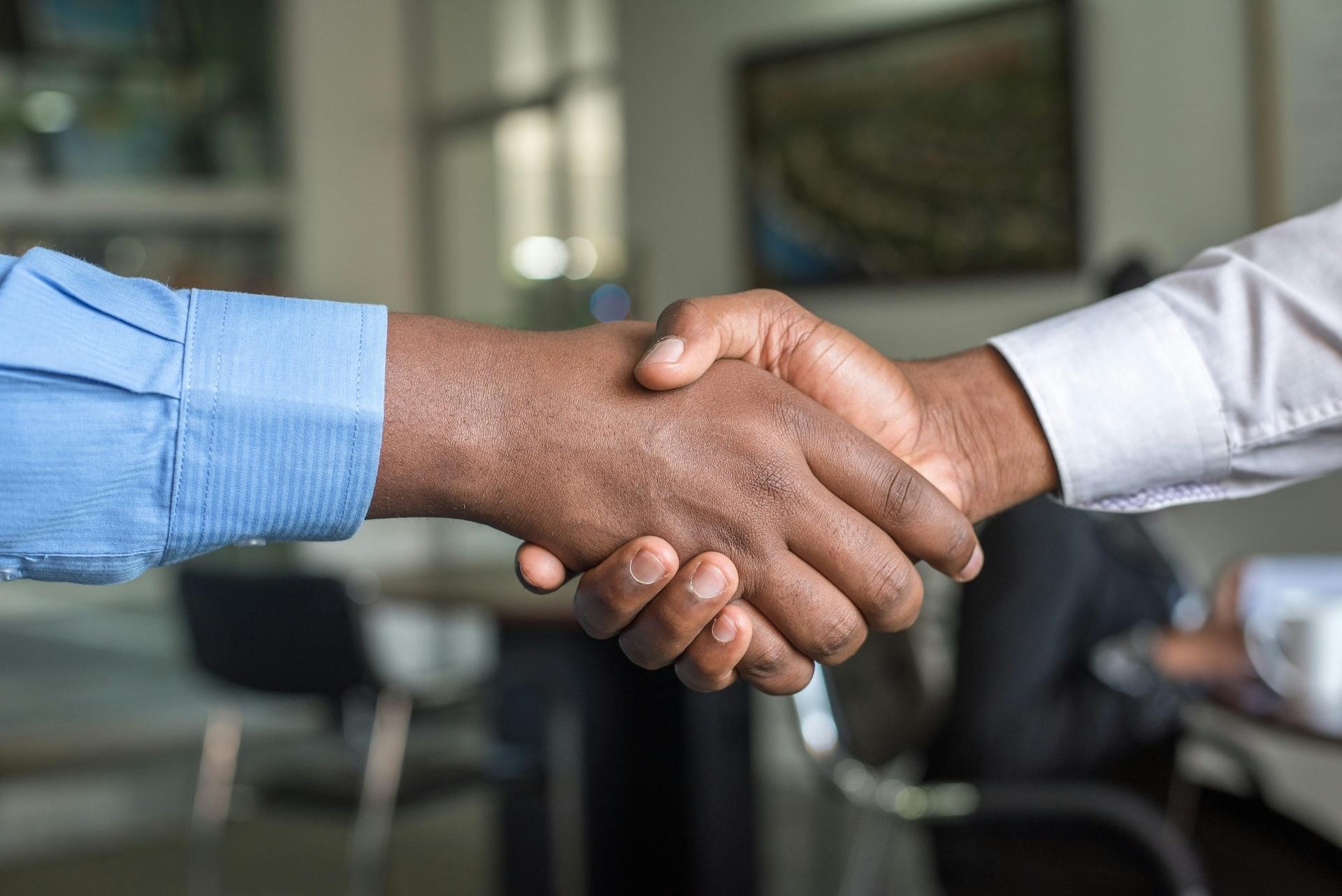 Close-up of business handshake between two people wearing blue and white shirts