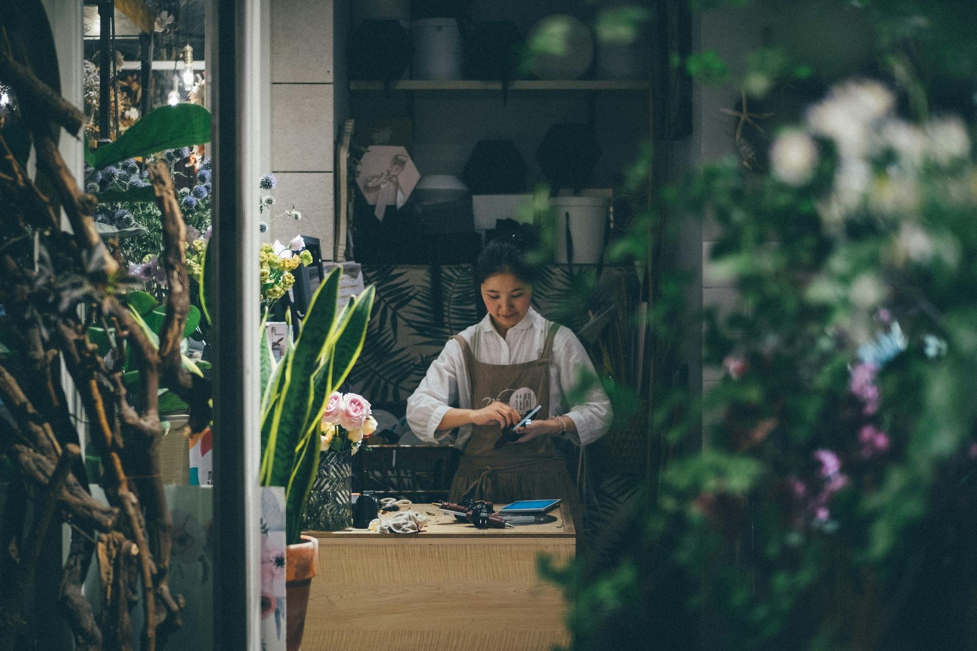 Scene of working on a project surrounded by lush plants and colorful flowers. The atmosphere is cozy, creative and full of greenery.